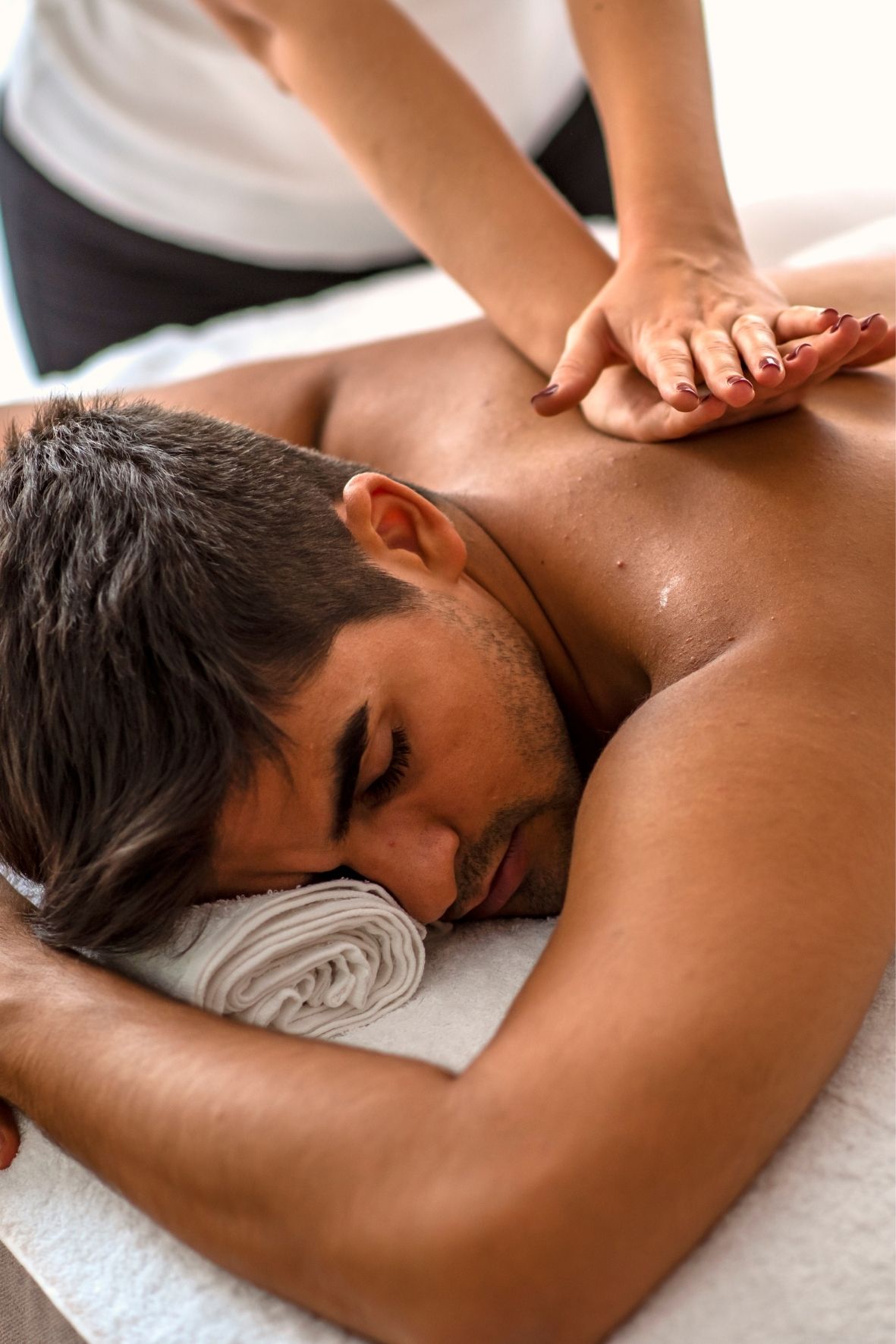 Table de massage recouverte d’un drap blanc dans un espace de massothérapie  à Farnham